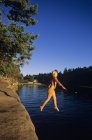 Teenage girl jumping from arenstone ledge, Vancouver Island, British Columbia, Canada . — Foto stock