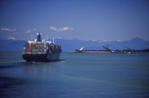 Navios de carga com montanhas costeiras além, Tsawwassen, Vancouver, British Columbia, Canadá . — Fotografia de Stock