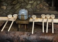 Cucharas de madera y fuente de purificación de agua pura en el Santuario Inari de Fushimi, Kioto, Japón - foto de stock