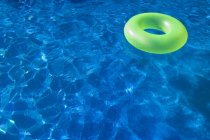 Anello galleggiante verde gonfiabile in piscina trasparente — Foto stock