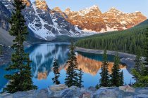 Mountains reflecting in water of Moraine Lake at dawn, Valley of Ten Peaks, Banff National Park, Alberta, Canada — Stock Photo