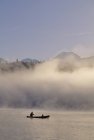 Male and child silhouettes in canoe on a misty summer morning, Alta Lake in Whistler, British Columbia, Canada — Stock Photo