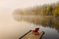 Cadeira Adirondack na doca de madeira do Lago Dickens, Saskatchewan, Canadá — Fotografia de Stock