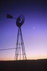 Pompe à eau éolienne et lune au crépuscule au Nouveau-Mexique, États-Unis — Photo de stock