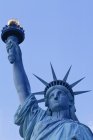 Vue en angle bas de la tête de Statue de la Liberté et détail de la torche contre le ciel bleu à New York, États-Unis — Photo de stock