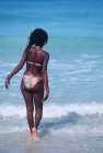 Vista trasera de la mujer local en bikini entrando en agua de mar, Veradaro, Cuba - foto de stock