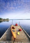 Задній вид чоловічого турист, відпочиваючи з Байдарка на човні док, Nutimik озеро Наметовий табір, Whiteshell Провінційний парк, Манітоба, Канада. — стокове фото