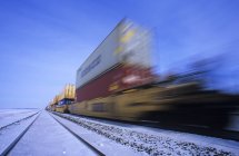 Conteneurs de fret sur un train en mouvement rapide avec flou en hiver près d'Oakbank, Manitoba, Canada — Photo de stock