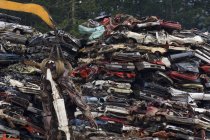 Gru che solleva auto appiattite da pile di auto obsolete nel cortile di riciclaggio, Vancouver Island, British Columbia, Canada — Foto stock