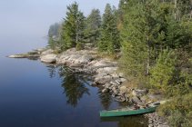 Rocky shoreline of French Lake with beached canoe in Quetico Provincial Park, Canada. — Stock Photo