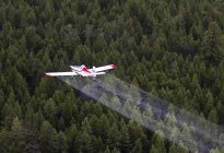 Agricultural plane spraying chemicals over spruce forest, British Columbia, Canada. — Stock Photo