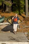 Mature woman carrying canoe to Source Lake, Algonquin Park, Ontario, Canada. — Stock Photo