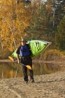Reifer Mann trägt Kanu vom Wasser, Ochsenzungensee, Muskoka, Ontario, Canada. — Stockfoto
