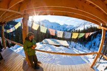 Uomo che si gode il caffè mattutino presso la baita di sci di fondo di Icefall Lodge, Golden, British Columbia, Canada — Foto stock