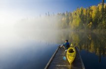 Mann sitzt auf Dock mit Kajak, dickens Lake, Northern saskatchewan, Kanada — Stockfoto
