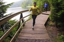 Uomo e donna che corrono sul lungomare presso Sasamat Lake, Belcarra Regional Park, Port Moody, British Columbia, Canada — Foto stock