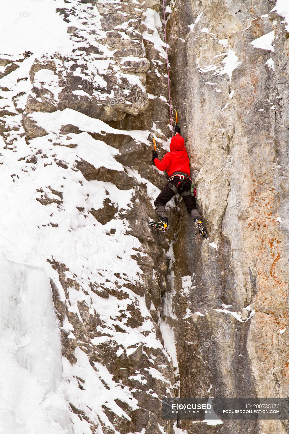 Young man climbs a mix of ice and rock while iceclimbing in Banff National Park near Banff