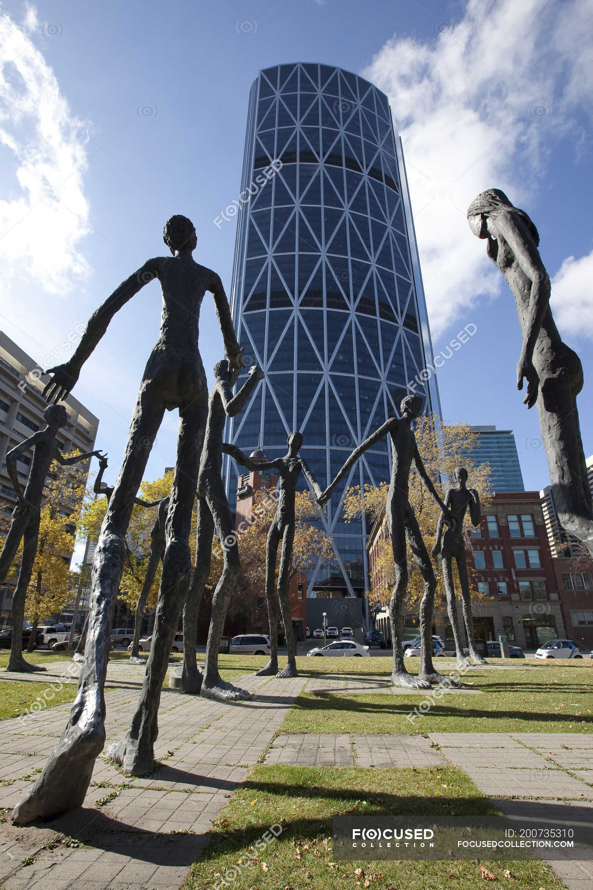 Family of Man sculptures against modern building in Calgary, Alberta, Canada. — skyscraper