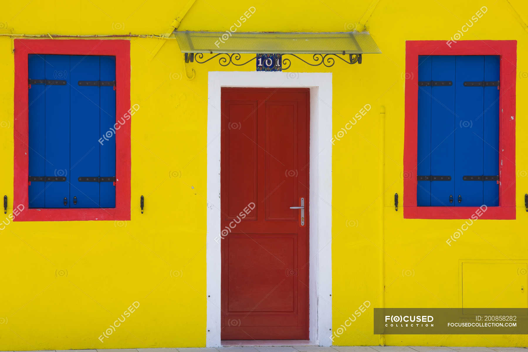 Bright yellow wall with door and windows — creative, colorful - Stock