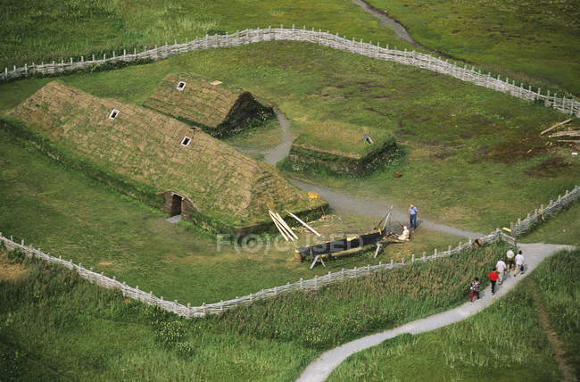 Vista aérea de los turistas caminando en Lanse aux meadows histórico asentamiento vikingo, Terranova, Canadá . - foto de stock