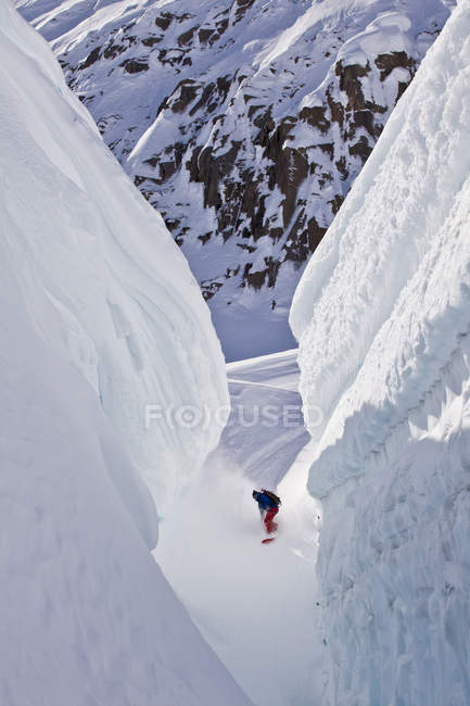 Мужской сплитбордер, проезжающий через расщелину на леднике, Лодж Айсфолл, Голден, Британская Колумбия, Канада — стоковое фото