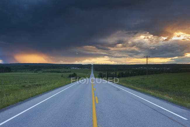 Thunderstorm clouds over straight highway near Water Valley, Alberta, Canada — Stock Photo