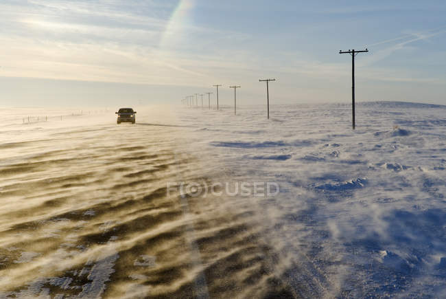 Car riding on road covered with blowing snow near Verwood, Saskatchewan, Canada — Stock Photo