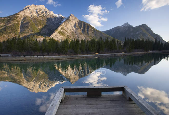 Wooden pier over water at lake with Mount Lorette in Kananaskis Country, Alberta, Canada. — Stock Photo