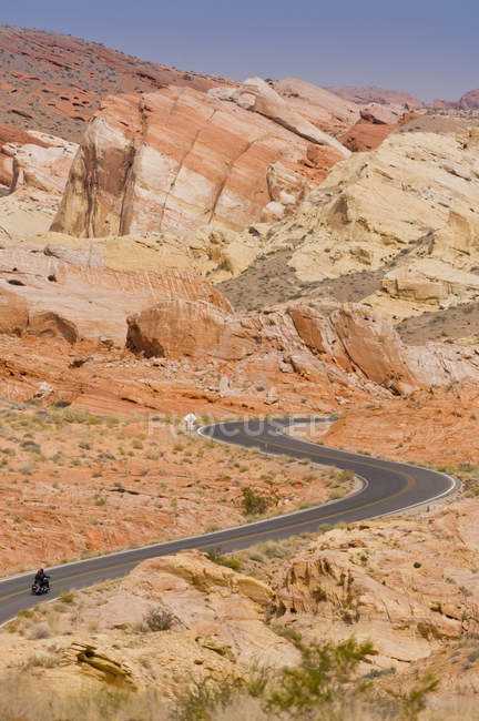 Persona de conducción de motocicletas en carretera en Valley of Fire State Park, Nevada, EE.UU. - foto de stock