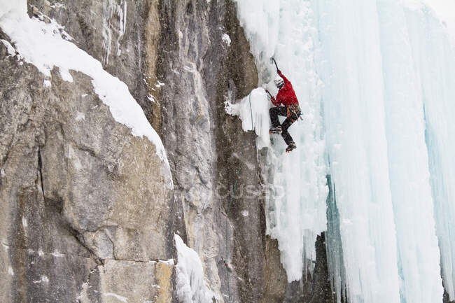 Young man climbs a mix of ice and rock while ice-climbing in Banff National Park near Banff, Alberta, Canada. — Stock Photo