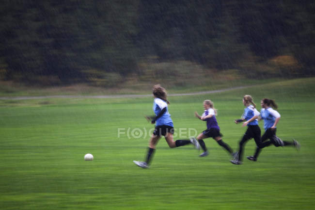 Equipe de futebol meninas jogando na chuva, Sunshine Coast, British Columbia, Canadá — Fotografia de Stock