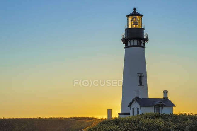 Faro di Yaquina Head sulla costa fiorita al tramonto in Oregon, USA — Foto stock