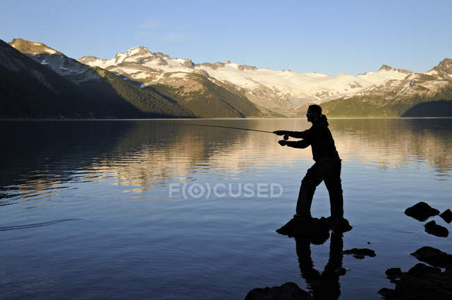 Силуэт человека, ловящего рыбу в сумерках, озеро Гарибальди, парк Гарибальди, Британская Колумбия, Канада — стоковое фото