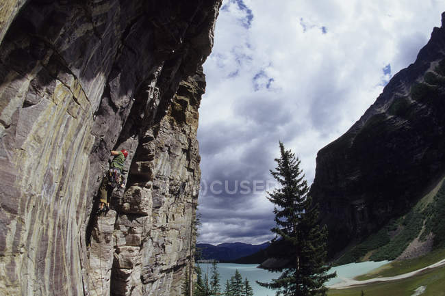 Climber working way up route overlooking beautiful Lake Louise, Alberta, Canada. — Stock Photo