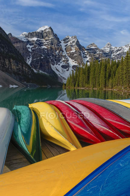 Canoas coloridas apiladas en el muelle del lago Moraine, Parque Nacional Banff, Alberta, Canadá - foto de stock