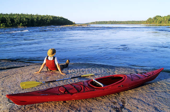 Rear view of male kayaker resting by Nutimik Lake, Whiteshell Provincial Park, Manitoba, Canada. — Stock Photo