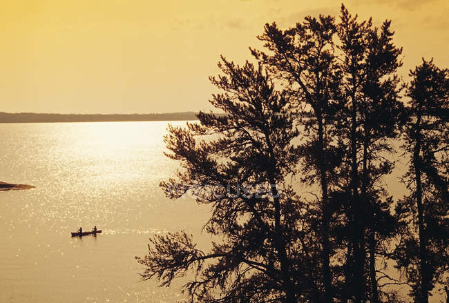 Silhouettes de personnes faisant du canot à travers le lac Big Whiteshell, parc provincial Whiteshell, Manitoba, Canada — Photo de stock