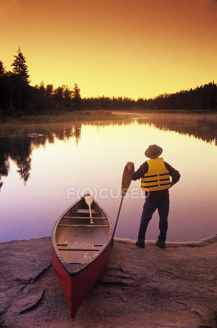 Задній вид чоловічий canoeist уздовж річки Whiteshell, Whiteshell Провінційний парк, Манітоба, Канада. — стокове фото