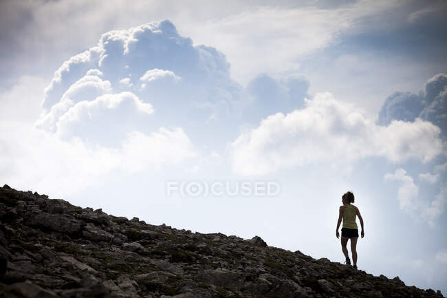 A young woman hiking along the Sulphur Skyline silhouetted against storm clouds. Miette Hotsprings, Jasper National Park, Alberta, Canada. — Stock Photo
