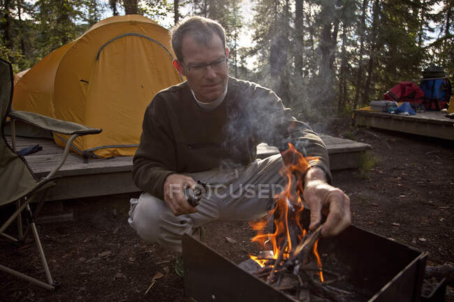 L'uomo di mezza età appicca il fuoco nel campeggio Virginia Falls, Nahanni National Park Preserve, NWT, Canada. — Foto stock