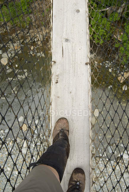 Pieds de randonneur traversant le pont suspendu du ruisseau Logan, sentier de la côte ouest, réserve de parc national Pacific Rim, île de Vancouver, Colombie-Britannique, Canada . — Photo de stock