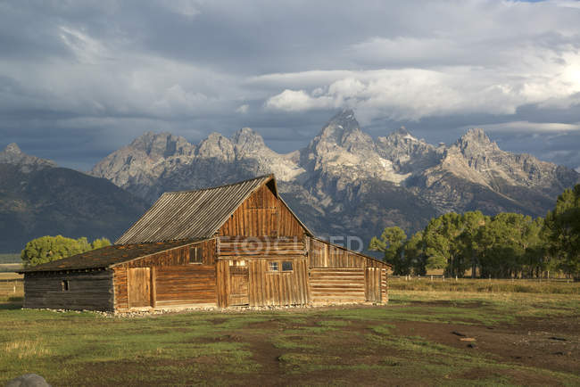Grange en bois avec chaîne de montagnes Grand Teton en arrière-plan, Parc national Grand Teton, États-Unis — Photo de stock