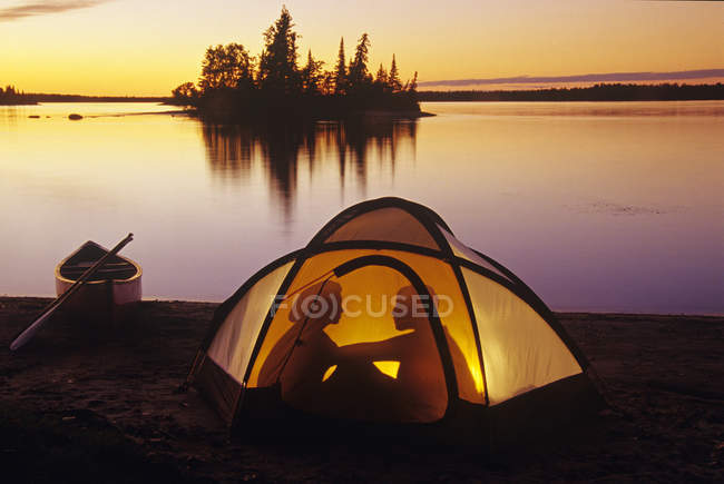 Silhouette di coppia campeggio in tenda a Otter Falls, Whiteshell Provincial Park, Manitoba, Canada
. — Foto stock