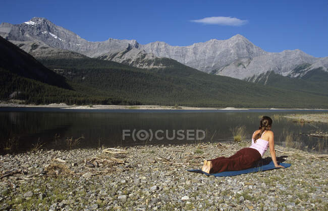Donna che pratica yoga lungo la riva dei laghi Spray, Kananaskis Country, Alberta, Canada . — Foto stock