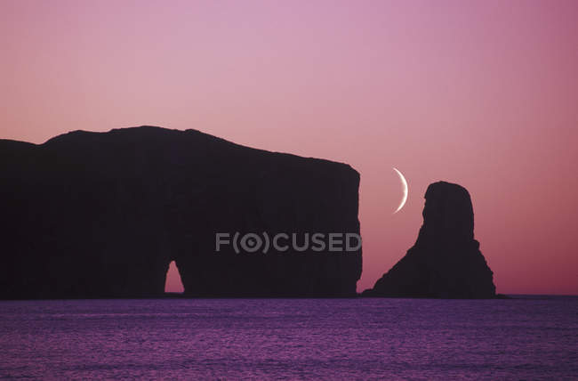 Perce Rock ao anoitecer com lua crescente, península de Gaspe, Quebec, Canadá . — Fotografia de Stock