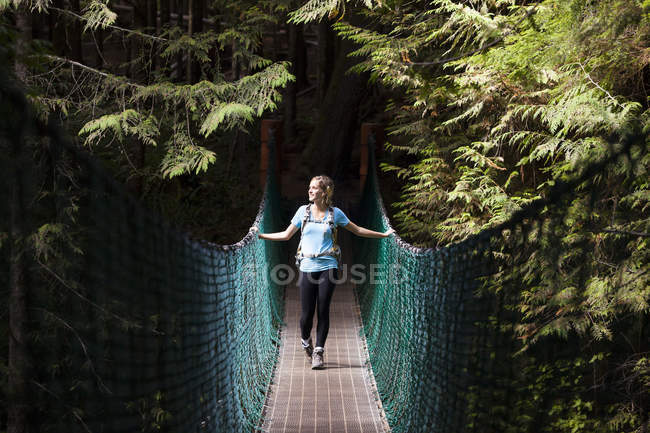 Giovane escursionista donna sul ponte sospeso tra China Beach e Mystic Beach lungo Juan de Fuca Trail, Isola di Vancouver, Canada . — Foto stock
