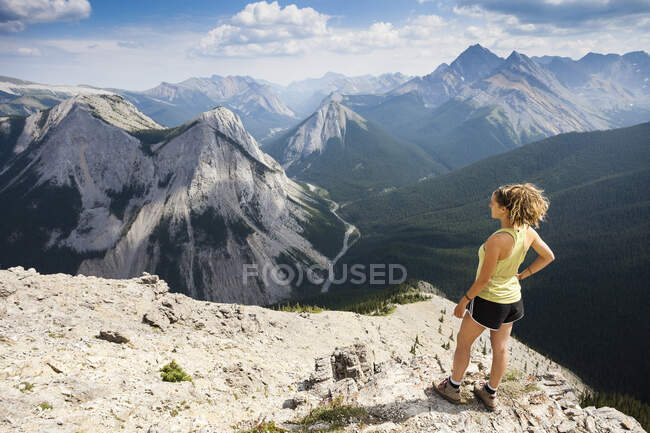 Uma jovem mulher está no cume do Sulphur Skyline Trail com vista para as Montanhas Rochosas. Miette Hotsprings, Jasper National Park, Alberta, Canadá. — Fotografia de Stock