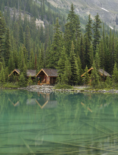 Cabañas de madera reflejadas en el agua del Lago Ohara, Parque Nacional Yoho, Columbia Británica, Canadá - foto de stock