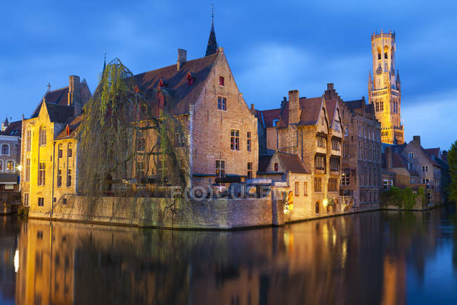 Edificios iluminados por la noche a lo largo del canal en el centro histórico de Brujas, Bélgica - foto de stock