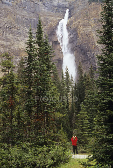 Une femme prend une photo des chutes Takakkaw dans les Rocheuses canadiennes, Yoho, Parc national, Colombie-Britannique, Canada — Photo de stock